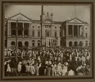 One of the old photographs featuring a centenary celebration. There is a huge crowd in front and inside a building. In the building's courtyard, there is a statue of Sir Stamford Raffles.