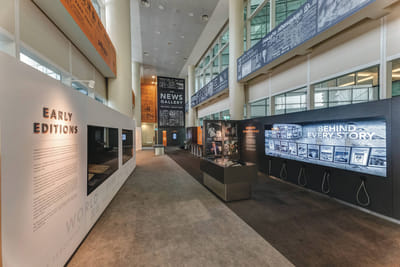 An overview of the News Gallery exhibition, which has showcases and tall multimedia screens.