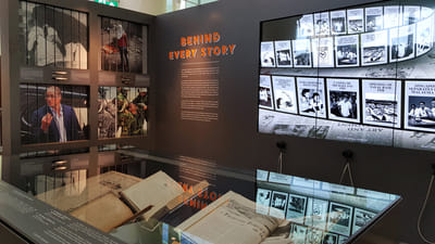 An overview of the News Gallery exhibition, which has showcases and tall multimedia screens.