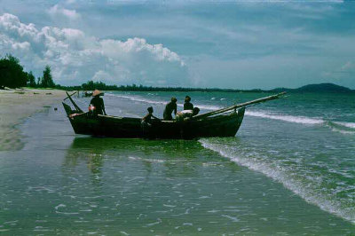 Five fisherman pushing a sampan out to sea.