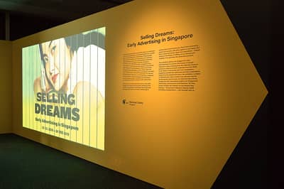 The exhibition introduction wall. A trivision-style video is projected onto the wall, next to the introduction text.