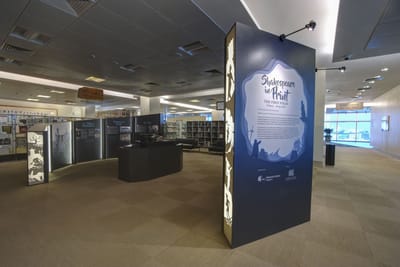 A photo of the main exhibition. The First Folio lies in the showcase in the middle, surrounded by informational walls.