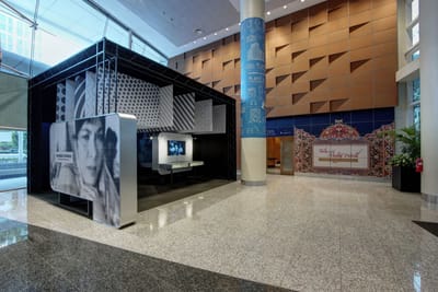 A photo of the Lobby exhibition. A large film still of an actress is on the side of the exhibition. Inside are TV screens showing old movies with there are showcases underneath.