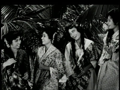 A black and white film still from the movie, 'Tun Fatimah'. Four women are smiling at each other.